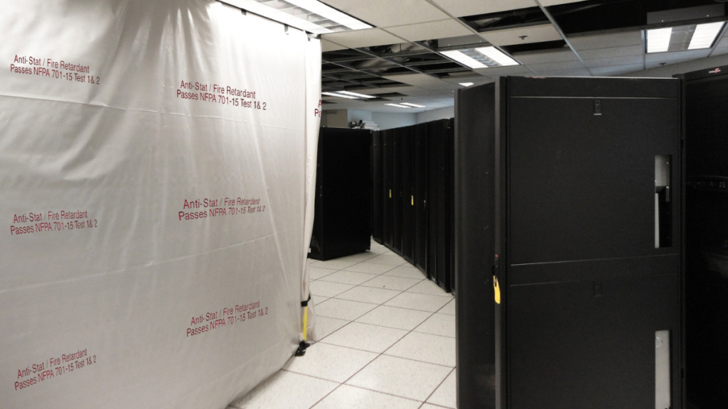 ASFR6 antistatic fire retardant plastic sheeting printed "Passes NFPA 701-15 Test 1 & 2" hung as a containment barrier beside server racks in a data center
