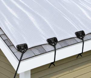 Shark Bite Tarp Grommet Fasteners securing reinforced plastic sheeting along a roof edge with tie-down cords.